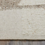 Close-up of a textured beige rug with subtle patterns on a wooden floor.