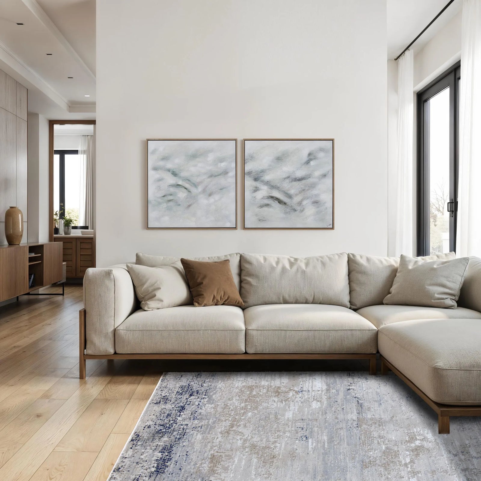 Modern living room with a beige sectional sofa, abstract art on the wall, and a rug.
