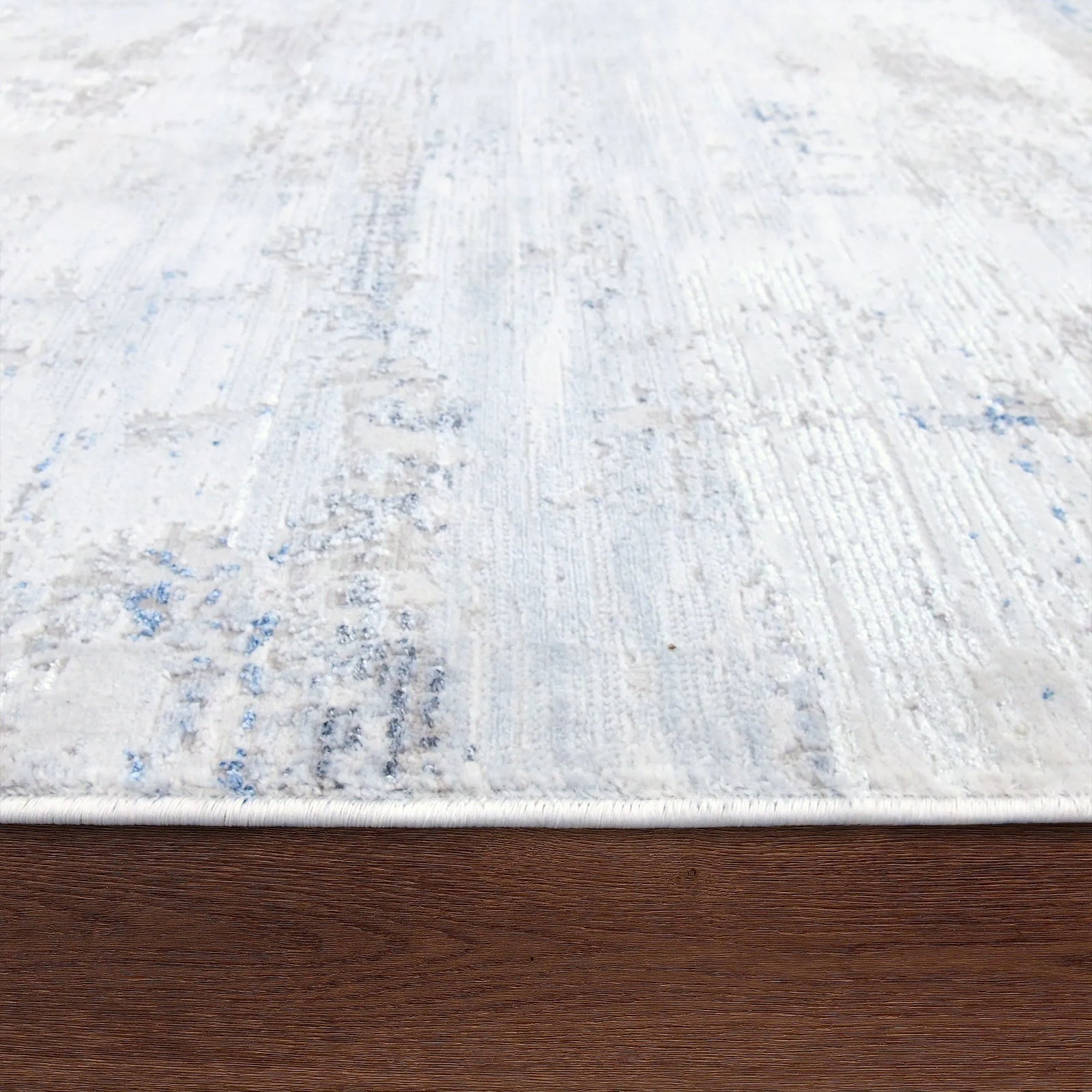 Textured white rug with blue specks on a wooden floor
