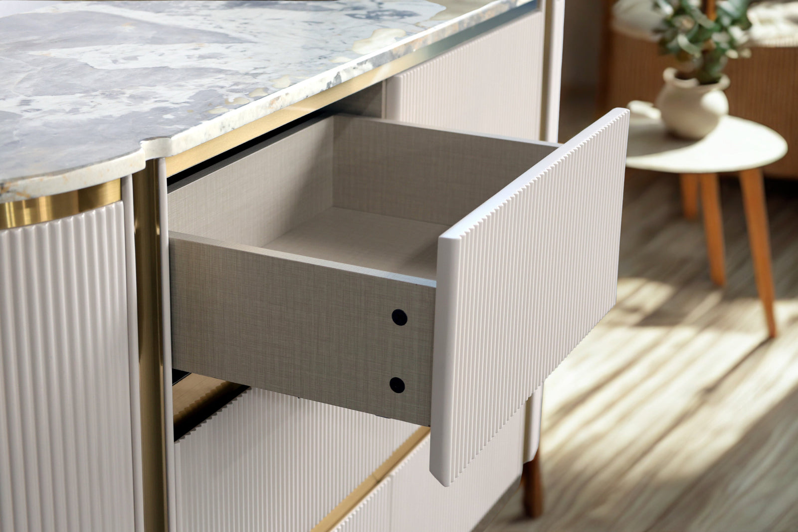 Close-up of a drawer being pulled out from a kitchen island with marble countertop.