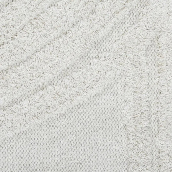 An off-white, hand woven cotton area rug with a geometric pattern and fringe edge.