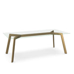 A clear glass top dining table with a brass accent base.