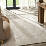 Beige area rug with geometric pattern in a room with a couch and table.