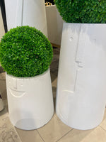 Two white, textured, rounded planters of different sizes, each containing a spherical artificial green plant.