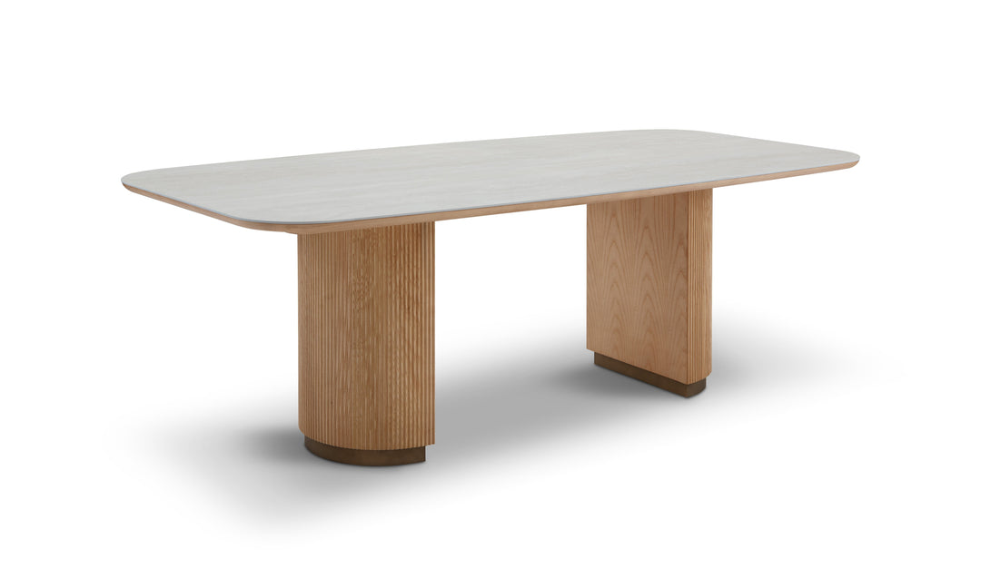 Modern dining table with light wood legs and a white top on a white background