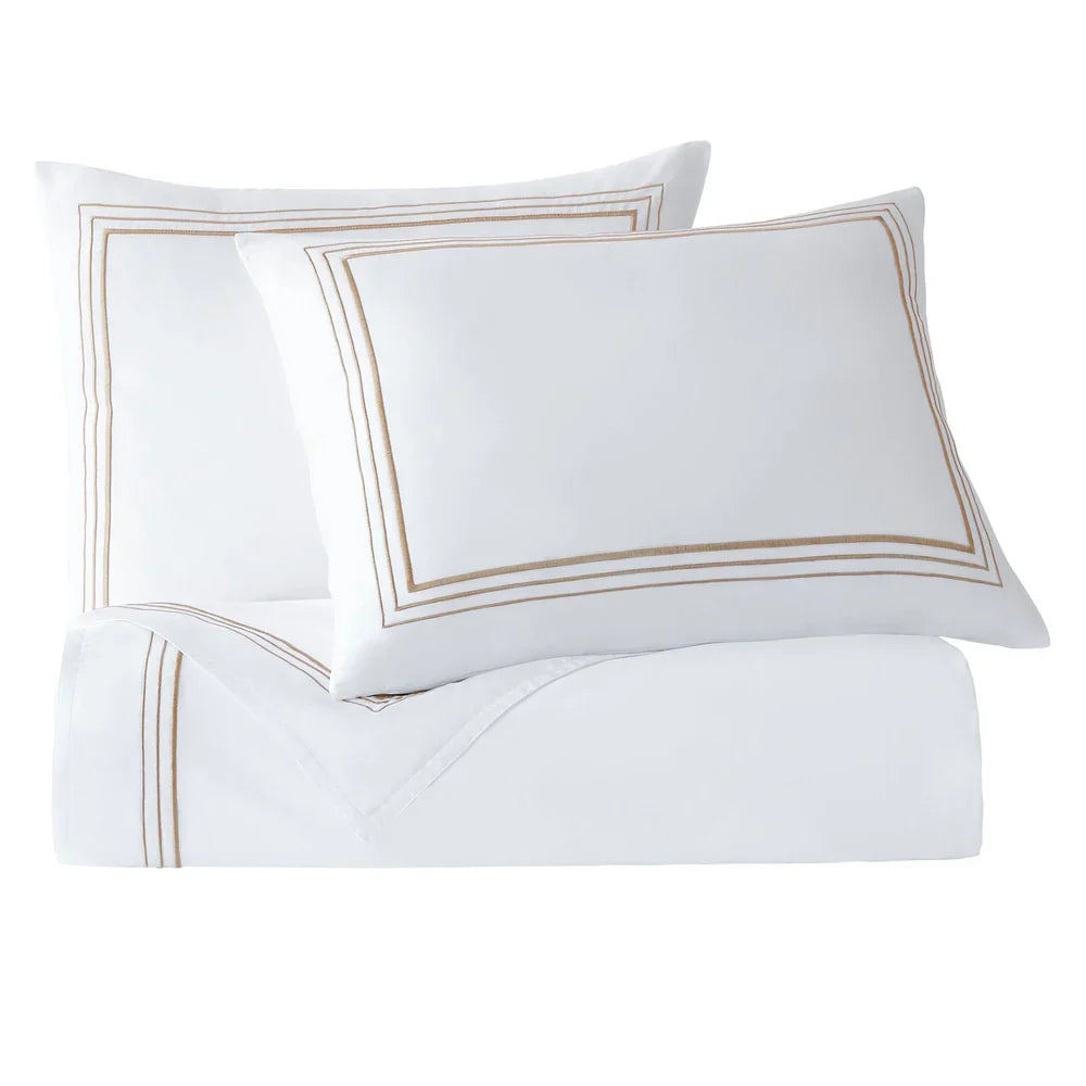 White pillows with gold trim on a white background