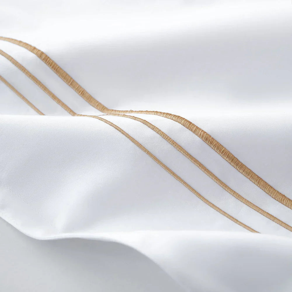 Close-up of white fabric with gold embroidery on a light gray background