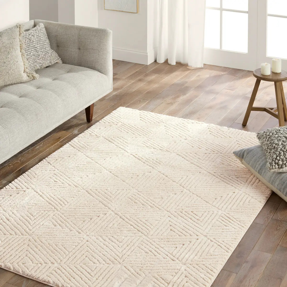 Living room with a textured beige rug, gray sofa, and wooden floor.