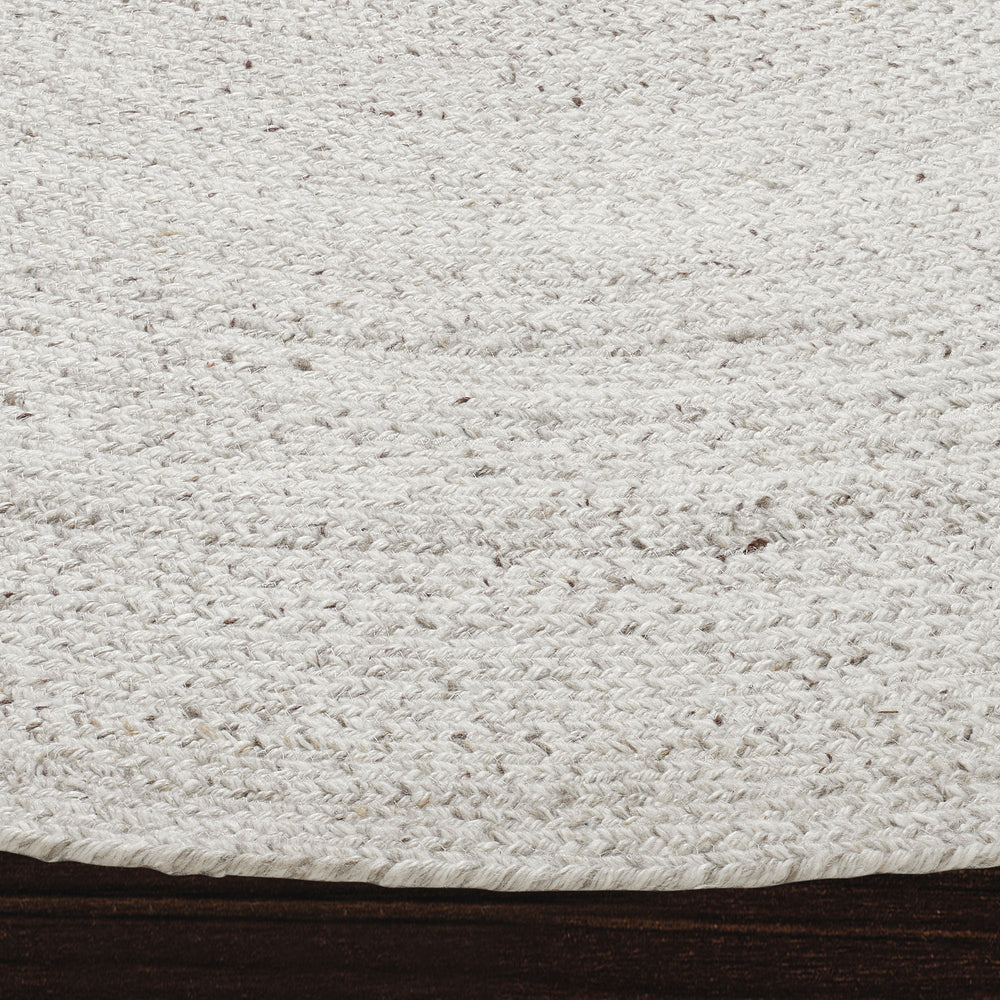 A round, beige area rug with a swirling geometric design