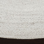 A round, beige area rug with a swirling geometric design