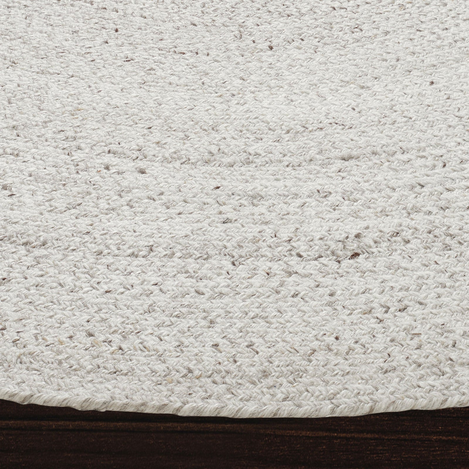 A round, beige area rug with a swirling geometric design