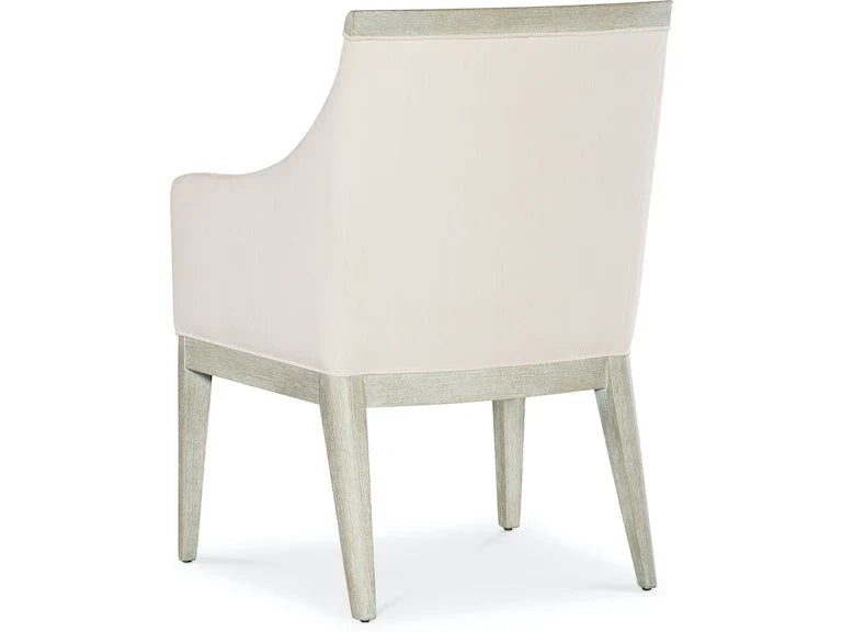 A beige upholstered dining chair with armrests and wooden legs, viewed from a front angle.