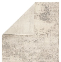 A power loomed area rug with a textured design in beige and gray tones.