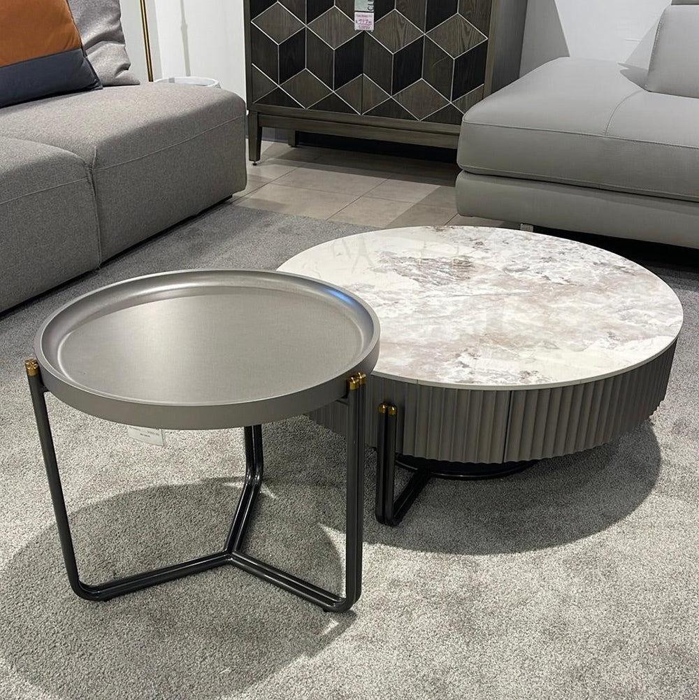 Two round coffee tables with a high-gloss finish, one large with a storage drawer and a small without, both with metal legs in a room setting.
