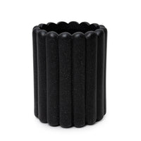 A black cylindrical fiberglass planter with a ribbed design.