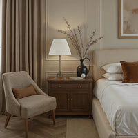 Neatly arranged bedroom with a bed, chair, lamp, and decorative elements.