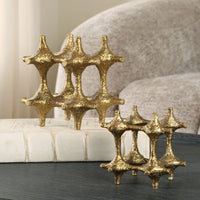 Two gold decorative pieces on a surface with a blurred background