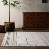 Living room with a patterned rug, wooden chest, and potted plants.