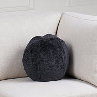 Round dark gray pillow on a light beige sofa