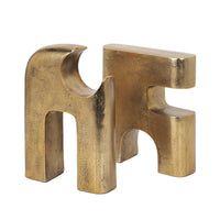 Gold metal sculpture of interlocking shapes on a white background