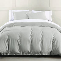 Gray comforter set on a bed with white pillows against a light-colored wall.