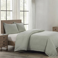 Bedroom with a bed featuring green bedding and wooden furniture.
