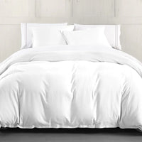White comforter set on a bed with light wooden headboard