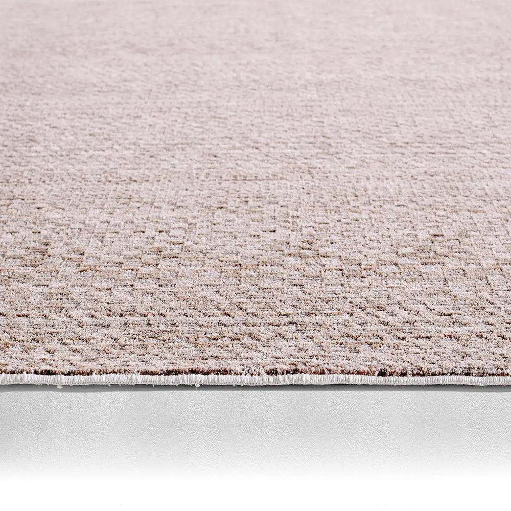 Close-up of a textured beige carpet border on a light gray background