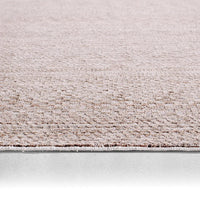 Close-up of a textured beige carpet border on a light gray background