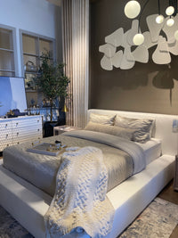 A white slipcover on a bed within a bedroom setting, with pillows and a quilt.