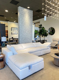 Modern living room with a white sectional sofa, ottoman, and decorative elements.