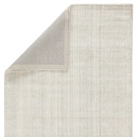 An ivory-colored area rug with a textured weave, partially showing its thickness and material.