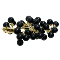 Black grape cluster brooch with gold accents on a white background