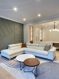 A modern white leather sectional sofa with a power headrest, placed in a stylishly decorated living room.
