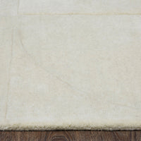 An ivory-colored wool area rug with a geometric patterned design, hand tufted with a cotton backing.