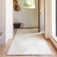White textured rug on a wooden floor with a neutral color scheme