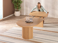Woman unfolding a wooden table in a room with a plant and striped rug.