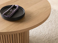 Wooden table with black plates and purple napkins on a neutral background