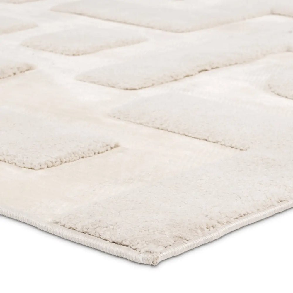 Close-up of a textured white rug with a diamond pattern on a light gray background