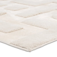 Close-up of a textured white rug with a diamond pattern on a light gray background