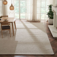 Beige area rug in a room with a dining table and chairs, large windows, and a fireplace.