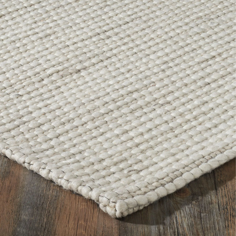 Close-up of a textured beige rug on a wooden floor