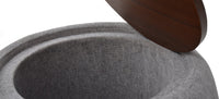 A round gray upholstered Roman ottoman with a cushioned top.