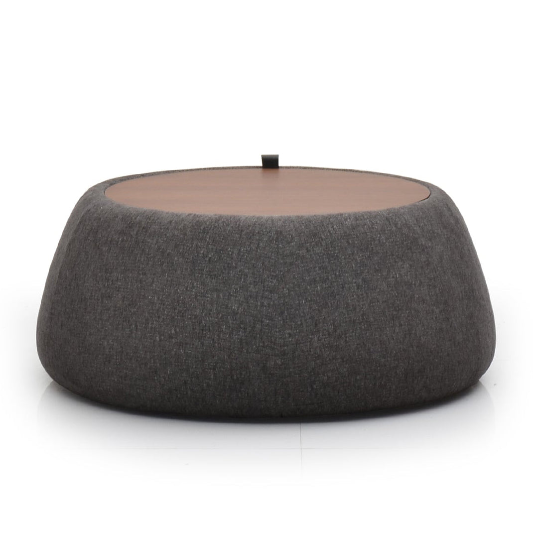 A gray fabric ottoman with a round top and a cylindrical body, placed against a white background.