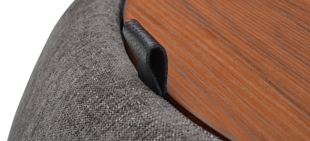 A gray fabric ottoman with a round top and a cylindrical body, placed against a white background.