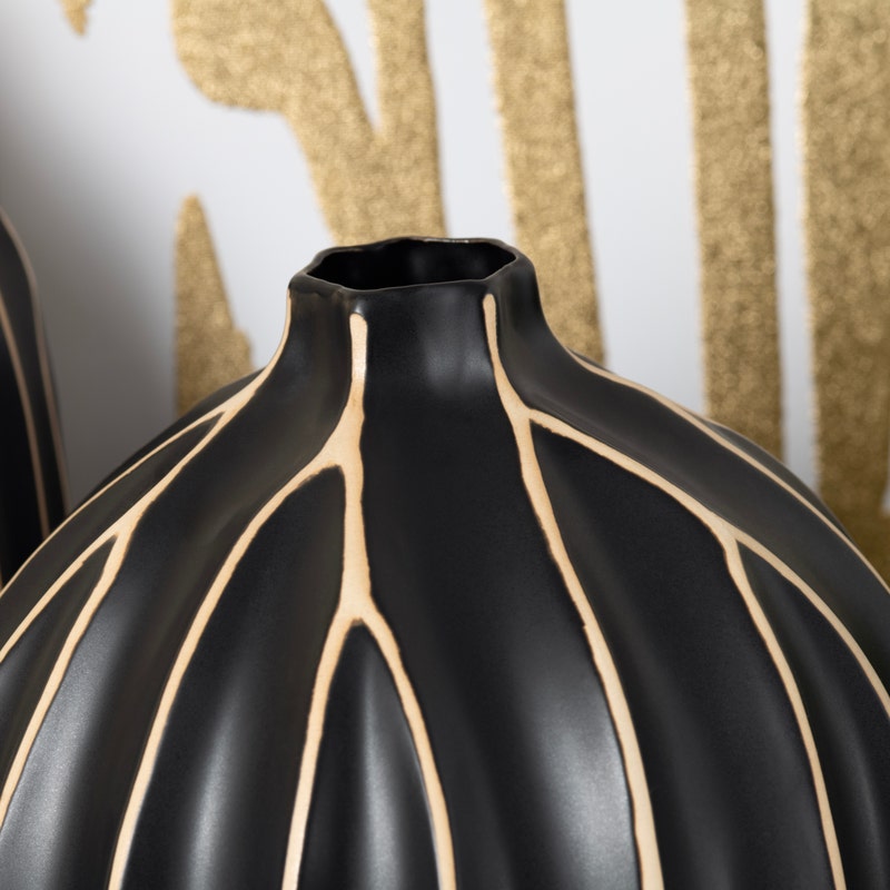 A black vases with vertical golden stripes.