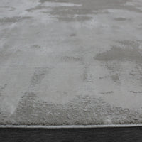 A rectangular jute rug with an abstract off-white and grey pattern.