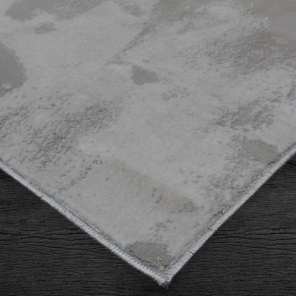 A rectangular jute rug with an abstract off-white and grey pattern.