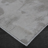 A rectangular jute rug with an abstract off-white and grey pattern.