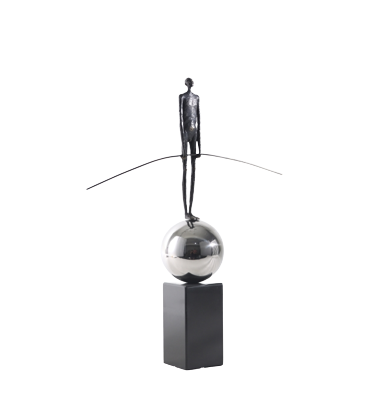 A decorative sculpture featuring a stylized figure with outstretched arms atop a geometric base.